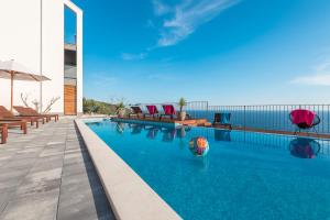 a pool with chairs and a ball in the water at Residence Delta in Cavtat