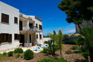 a large white building with tables and chairs in a yard at Boa Vista San Vito - Area Fitness, Barbecue Area, Tennis Court in San Vito lo Capo