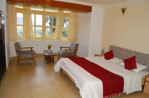 a bedroom with a bed and two chairs and windows at KSTDC Hotel Mayura Sudarshan ,Ooty in Ooty