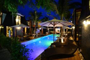 a swimming pool with chairs and umbrellas at night at Bukit Pool Villas - SHA Extra Plus in Patong Beach