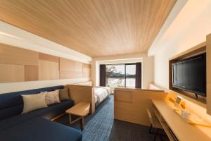 a hotel room with a couch and a tv at Izumigo AMBIENT Tateshina Hotel in Tateshina