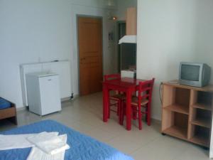 a small room with a red table and a television at Eleni Palace in Amoudara Herakliou