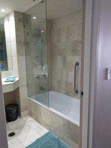 a bathroom with a tub and a glass shower at High Floor Ocean View at Surfers Paradise - Hotel Studio in Gold Coast
