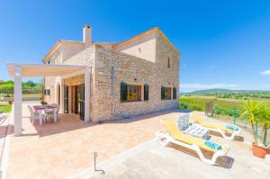 an outdoor patio with lounge chairs and a house at Angigal in Manacor