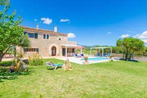 a stone house with a yard with a pool at Angigal in Manacor