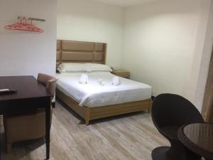 1 dormitorio con cama, escritorio y mesa en Jeamco Royal Hotel-Palawan, en Puerto Princesa City