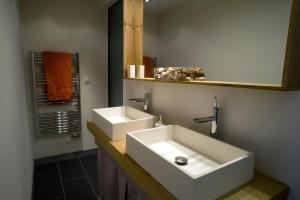 La salle de bains est pourvue de 2 lavabos blancs et d'un miroir. dans l'établissement Villa des Canuts, à Lyon