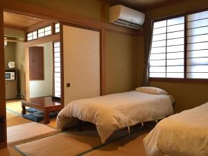 1 dormitorio con 2 camas, mesa y ventanas en Hakuba Landmark Happo Lodge, en Hakuba