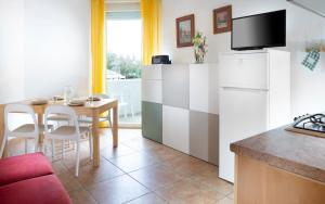 a kitchen with a table and a white refrigerator at SoleMare Hotel e Residence in Misano Adriatico