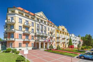 duży budynek z zaparkowanym przed nim samochodem w obiekcie Spa Resort PAWLIK-AQUAFORUM we Franciszkowych Łaźniach