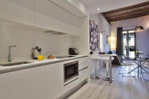 una cocina con armarios blancos y una mesa con sillas. en Habitat Apartments ADN, en Barcelona