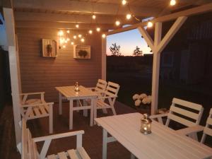 a porch with a table and chairs and lights at Domki Letniskowe Gris in Grzybowo