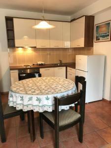 a kitchen with a table and chairs and a white refrigerator at Apartment Pulić in Rab