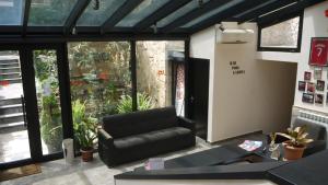 a living room with a black leather couch and windows at Sani Hotel in Tbilisi City