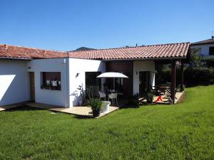 une maison blanche avec un parasol et une cour dans l'&eacute;tablissement Maison Fleurie, &agrave; Uhart-Cize