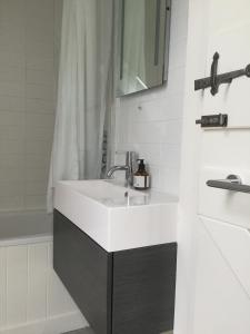 a bathroom with a white sink and a bath tub at Orford Lodge Barn in Orford