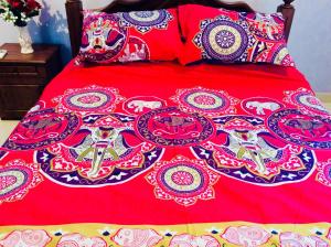 1 cama con edredón rojo y almohadas en Northwood Residence - Marawila, en Marawila