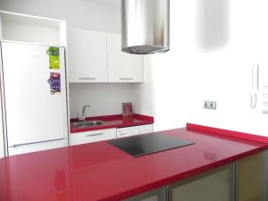 a red kitchen with a sink and a refrigerator at Apt. Eros in Conil de la Frontera