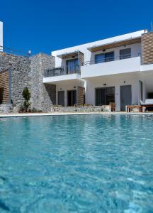 a villa with a swimming pool in front of a house at Seascape Luxury Residences in Agia Pelagia