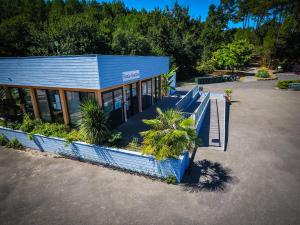 ein blaues Gebäude mit Palmen davor in der Unterkunft Village Vacances Les Genêts in Léon