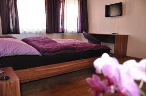 a bedroom with a bed with purple sheets and a desk at Gästezimmer Michelangelo in Rothenburg ob der Tauber