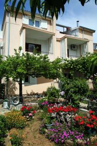 a building with a flower garden in front of it at Apartments & Rooms Samohod in Vodice