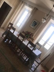 a dining room table with two chairs and two windows at A Balamata in Cervione