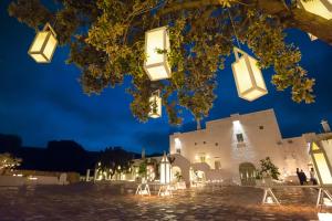 a building with lights hanging from a tree at night at Masseria Le Carrube in Ostuni