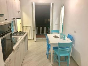 a kitchen with a white table and blue chairs at Chiaro di Luna in Maiori