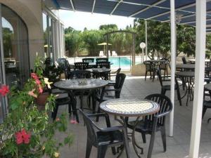 an outdoor patio with tables and chairs and a pool at Les Mimosas in Lunel