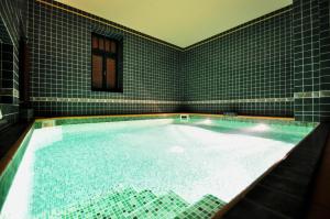 a large swimming pool in a bathroom with a tile wall at Grand Hotel Praha in Jičín