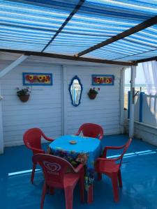 eine Terrasse mit einem blauen Tisch und zwei roten Stühlen in der Unterkunft La veranda in Ardea