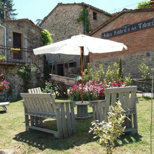 a table with an umbrella and two benches at Podere Casina Rossa in Poppi