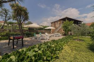 einen Garten mit Stühlen, Tischen und Sonnenschirmen in der Unterkunft Casa da Tia Palmira in Castelo de Paiva