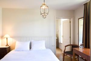 a bedroom with a white bed and a desk and a lamp at Oranje City Hotel in Diest