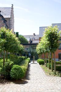 a brick walkway with trees and bushes in front of a building at Oranje City Hotel in Diest