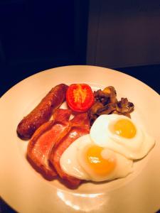 un plato de desayuno con huevos, salchichas y tocino en Eslington Villa en Gateshead