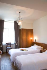 a hotel room with two beds and a chandelier at Oranje City Hotel in Diest