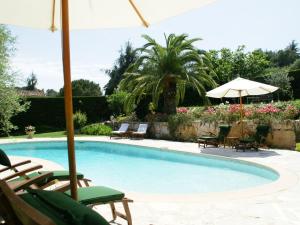 a swimming pool with chairs and an umbrella at Stunning villa with heated swimming pool air conditioning and large private enclosed garden in Valbonne