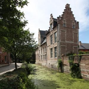 un vieux bâtiment en briques avec une cour en herbe devant lui dans l'établissement Oranje City Hotel, à Diest