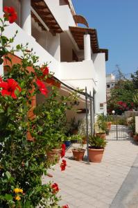 un edificio bianco con fiori e piante rossi di Residence Hotel Baia Portinenti a Città di Lipari
