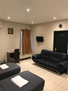 a living room with a black couch and a tv at Royal Hotel in Brussels