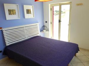 - une chambre dotée d'un lit avec un mur bleu dans l'établissement Appartementi di Lu, à Marina di San Lorenzo