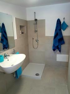 La salle de bains est pourvue d'un lavabo et d'une douche avec des serviettes bleues. dans l'établissement Appartementi di Lu, à Marina di San Lorenzo
