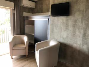 een woonkamer met 2 stoelen en een tv aan de muur bij Stella Marina in Galeria