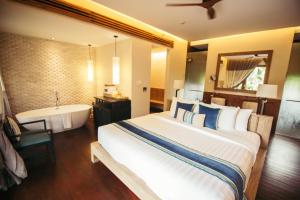 a bedroom with a large bed and a bath tub and a sink at Anantaya Resort and Spa Passikudah in Pasikuda