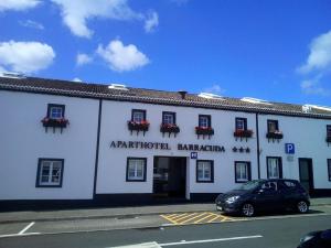 a white building with a car parked in front of it at Aparthotel Barracuda in Ponta Delgada