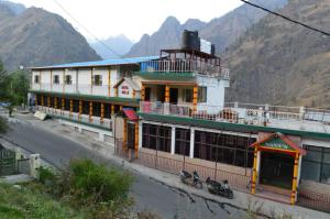 a building on the side of a street with mountains at Hotel Auli D in Joshīmath