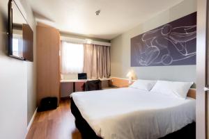 a hotel room with a large bed and a desk at Ibis Granada in Granada