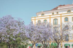 a building with purple trees in front of it at Loule Jardim Hotel in Loulé